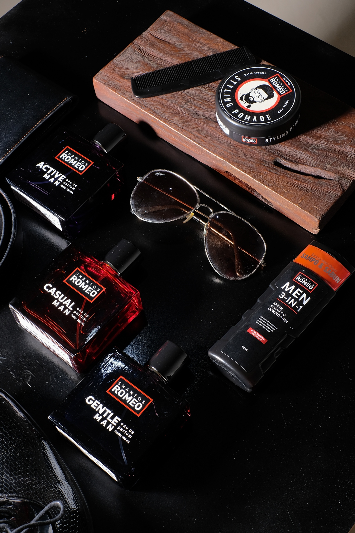 “Flat lay grooming Shantos Romeo: 3-in-1 wash, pomade, parfum, sunglasses”